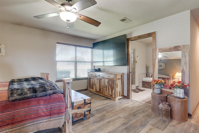 bedroom with light hardwood / wood-style floors, ceiling fan, a textured ceiling, and ensuite bathroom