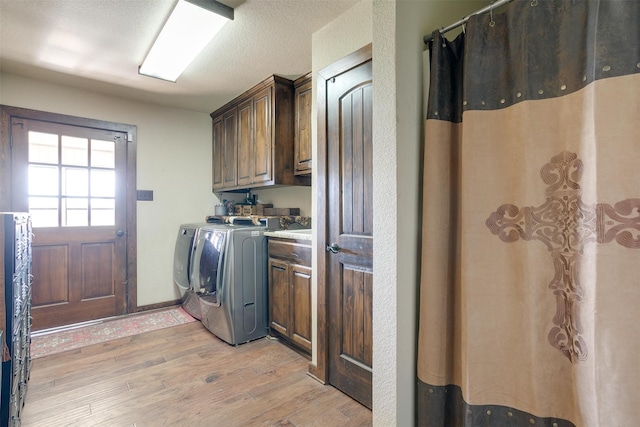 clothes washing area with cabinets, a textured ceiling, light hardwood / wood-style flooring, and independent washer and dryer