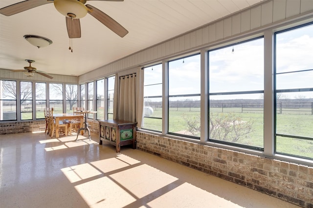 unfurnished sunroom with a rural view, ceiling fan, and plenty of natural light