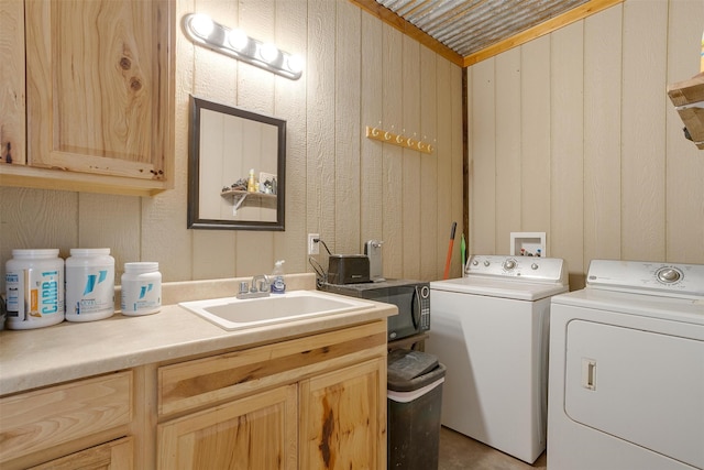 clothes washing area featuring wood walls, cabinets, sink, and washer and dryer