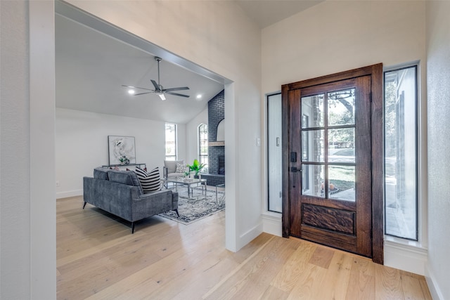 entryway with a brick fireplace, high vaulted ceiling, light hardwood / wood-style floors, and ceiling fan