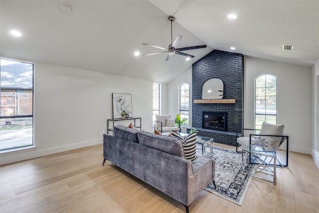 living room with light hardwood / wood-style floors, vaulted ceiling, a fireplace, and ceiling fan