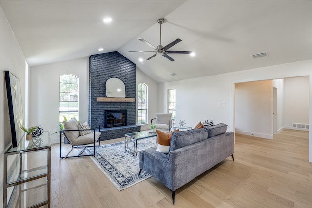 living room with vaulted ceiling, light hardwood / wood-style flooring, a fireplace, and ceiling fan