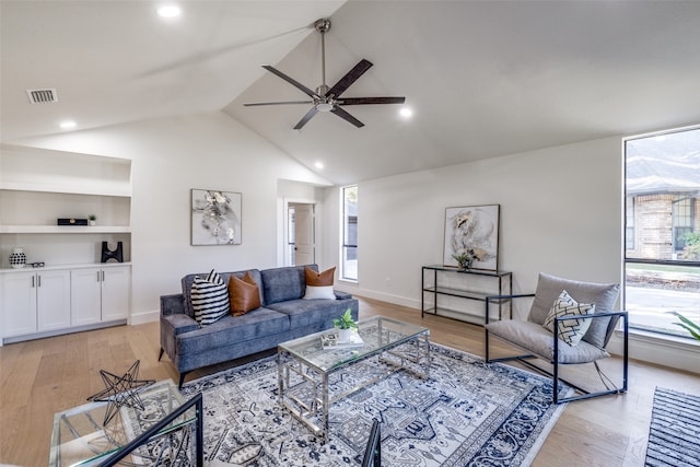 living room with vaulted ceiling, built in shelves, light wood-type flooring, and ceiling fan