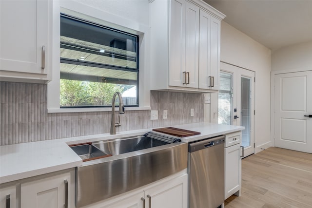 kitchen with stainless steel dishwasher, backsplash, white cabinets, and light hardwood / wood-style floors