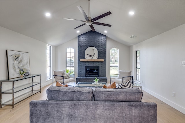 living room with vaulted ceiling, light hardwood / wood-style flooring, a fireplace, and ceiling fan