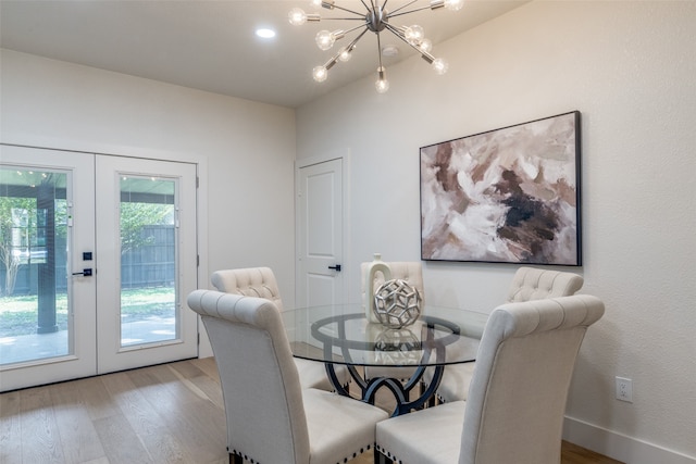 dining area with a chandelier, french doors, and light wood-type flooring