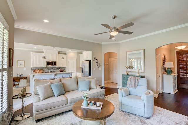 living room featuring crown molding, ceiling fan, and dark hardwood / wood-style flooring