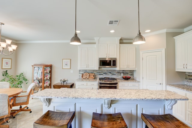 kitchen with pendant lighting, white cabinets, a kitchen bar, and stainless steel appliances