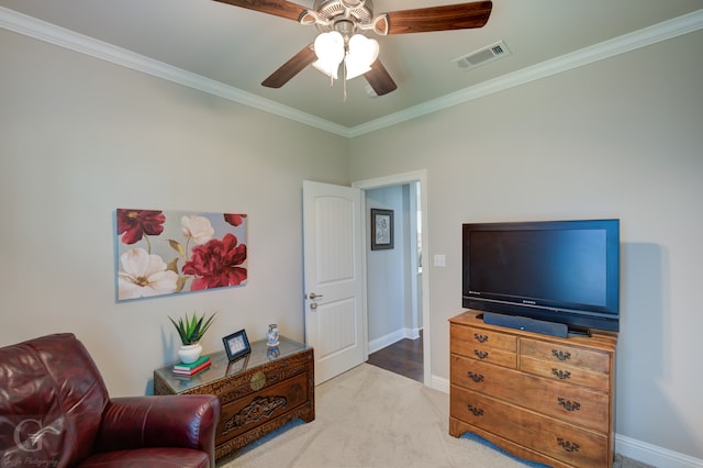 living area with ceiling fan, crown molding, and light colored carpet