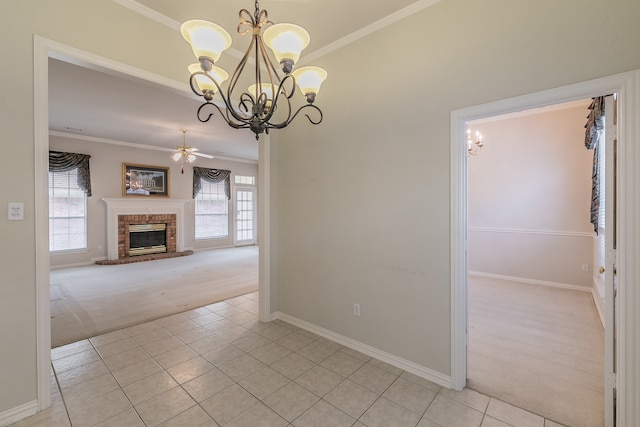 unfurnished dining area with crown molding, light colored carpet, ceiling fan with notable chandelier, and a brick fireplace