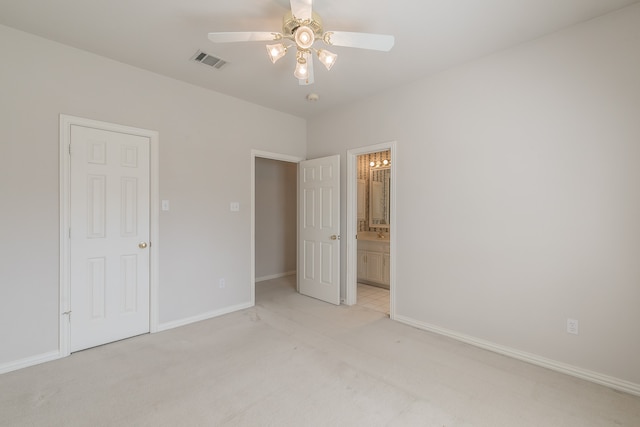 unfurnished bedroom with ceiling fan, light colored carpet, and ensuite bath