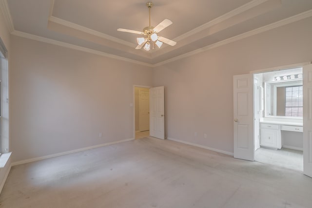 unfurnished bedroom with a tray ceiling, ceiling fan, light colored carpet, and ornamental molding