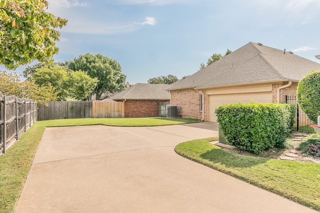 view of front of property with central air condition unit, a front yard, and a garage