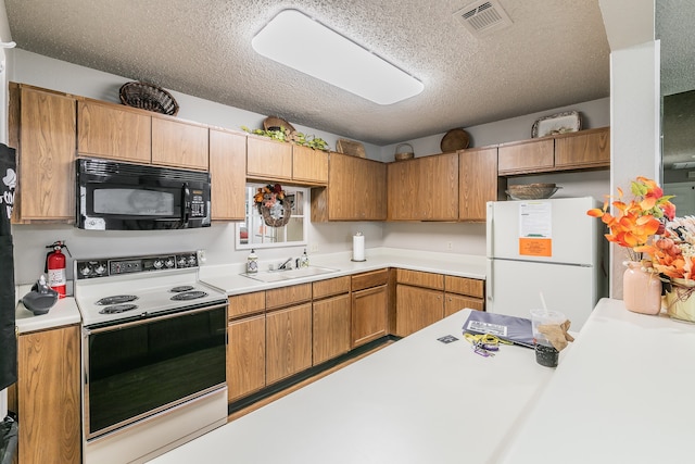 kitchen featuring sink, white appliances, and a textured ceiling