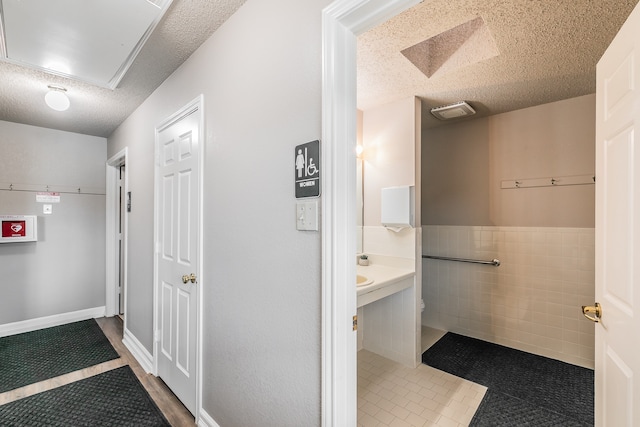 bathroom featuring tile patterned flooring, a textured ceiling, and tile walls