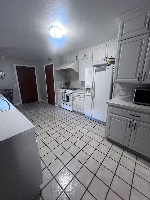 kitchen with white appliances, sink, a textured ceiling, white cabinets, and light tile patterned floors