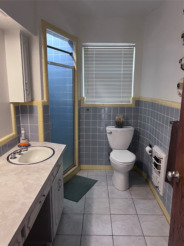 bathroom with walk in shower, tile walls, toilet, vanity, and tile patterned floors