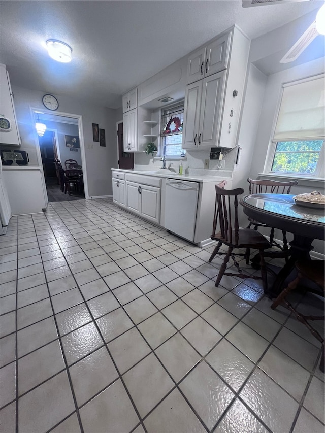 kitchen featuring white cabinets, light tile patterned floors, a textured ceiling, white dishwasher, and sink