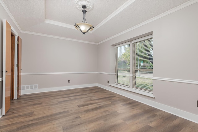 spare room with a textured ceiling, dark hardwood / wood-style floors, crown molding, and a tray ceiling