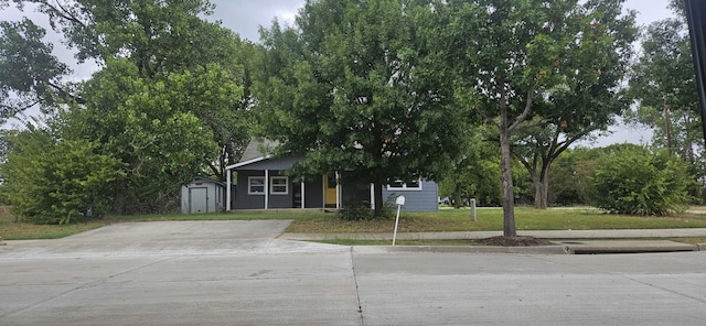 obstructed view of property with a front yard and a storage shed