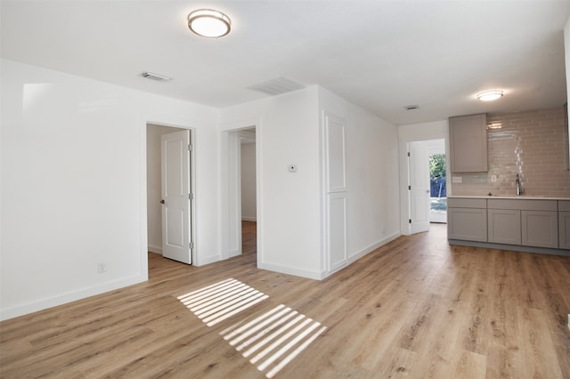 unfurnished living room with light hardwood / wood-style flooring and sink