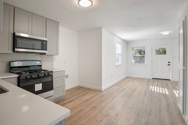 kitchen featuring decorative backsplash, light wood-type flooring, and appliances with stainless steel finishes