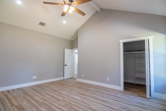 unfurnished bedroom with a spacious closet, ceiling fan, beamed ceiling, light hardwood / wood-style floors, and a closet