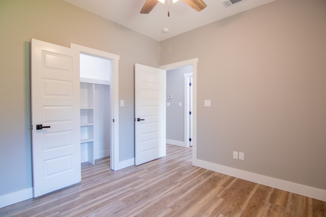 unfurnished bedroom with ceiling fan, light wood-type flooring, and a closet