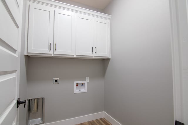 washroom featuring electric dryer hookup, hardwood / wood-style flooring, cabinets, and washer hookup