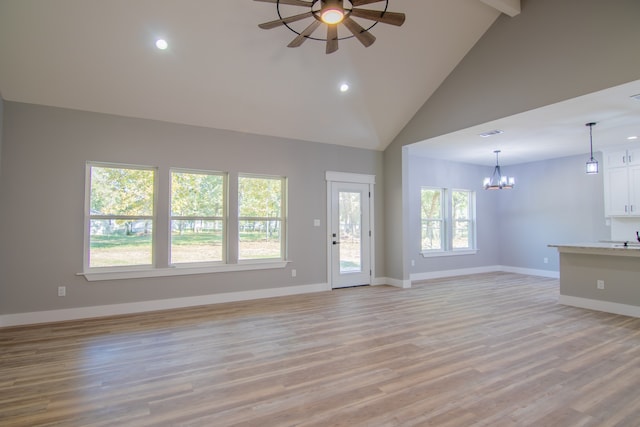 unfurnished living room featuring beam ceiling, high vaulted ceiling, ceiling fan with notable chandelier, and light wood-type flooring