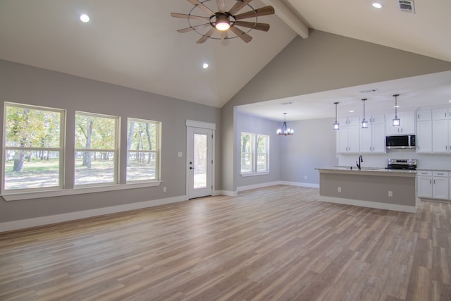 unfurnished living room featuring high vaulted ceiling, ceiling fan with notable chandelier, sink, light wood-type flooring, and beam ceiling