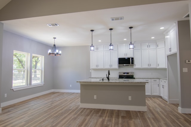 kitchen with light stone countertops, stainless steel appliances, a center island with sink, white cabinets, and hanging light fixtures