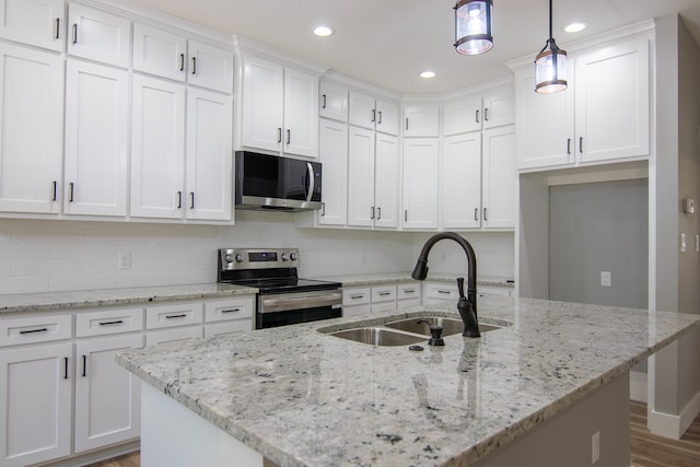 kitchen featuring sink, hanging light fixtures, stainless steel appliances, an island with sink, and white cabinets