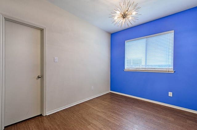 spare room with dark wood-type flooring and a notable chandelier