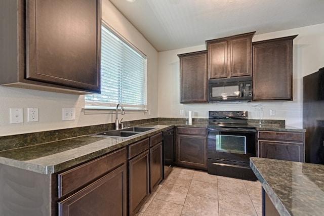 kitchen with sink, black appliances, dark brown cabinetry, and dark stone counters