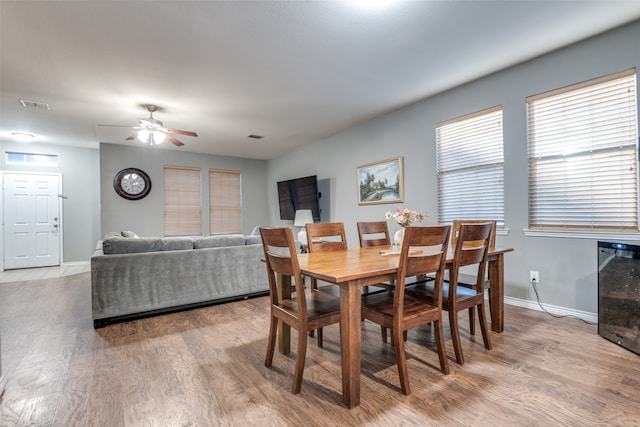 dining space with beverage cooler, light wood-type flooring, and ceiling fan