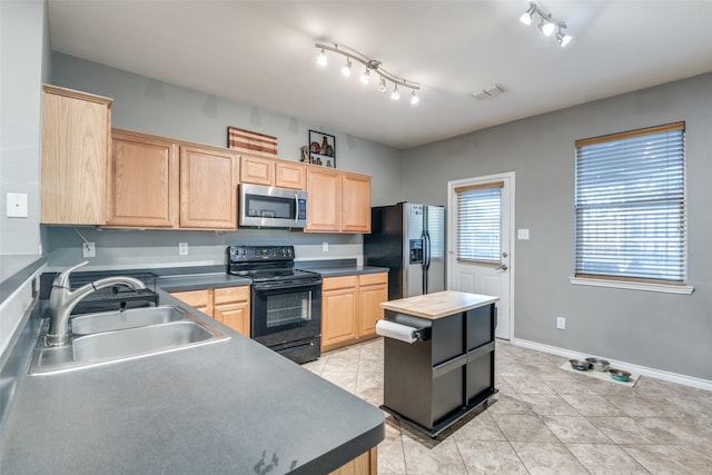 kitchen featuring light brown cabinetry, sink, stainless steel appliances, and a kitchen island