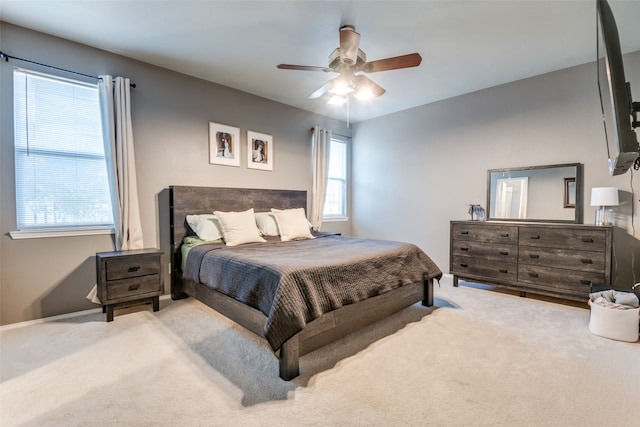 bedroom featuring ceiling fan, multiple windows, and light colored carpet