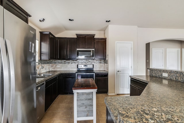 kitchen featuring vaulted ceiling, decorative backsplash, light tile patterned flooring, sink, and appliances with stainless steel finishes