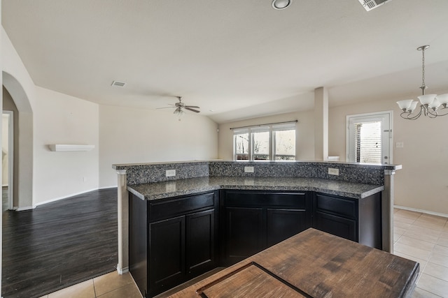 kitchen featuring ceiling fan with notable chandelier, a center island, decorative light fixtures, dark stone countertops, and light tile patterned floors