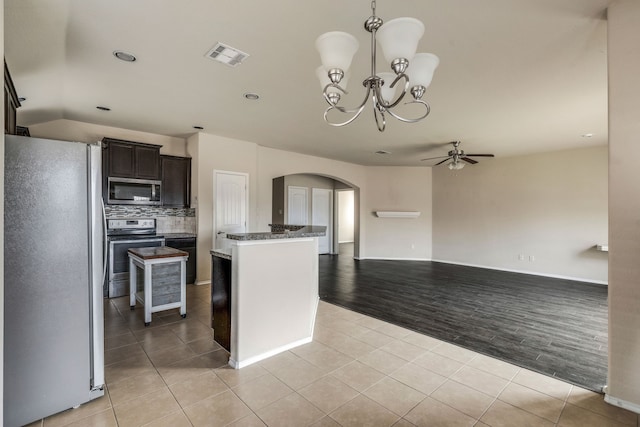 kitchen featuring light tile patterned floors, appliances with stainless steel finishes, a center island, and dark brown cabinets