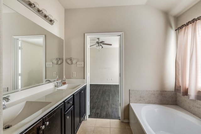 bathroom with tile patterned floors, vanity, a tub to relax in, vaulted ceiling, and ceiling fan