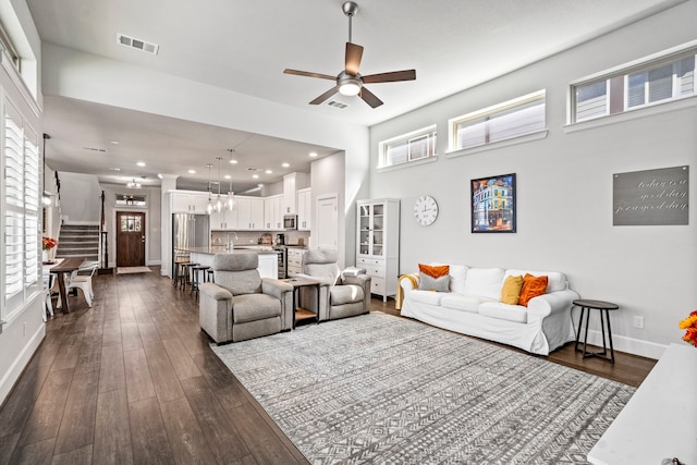 living room featuring dark hardwood / wood-style floors, ceiling fan, a towering ceiling, and sink