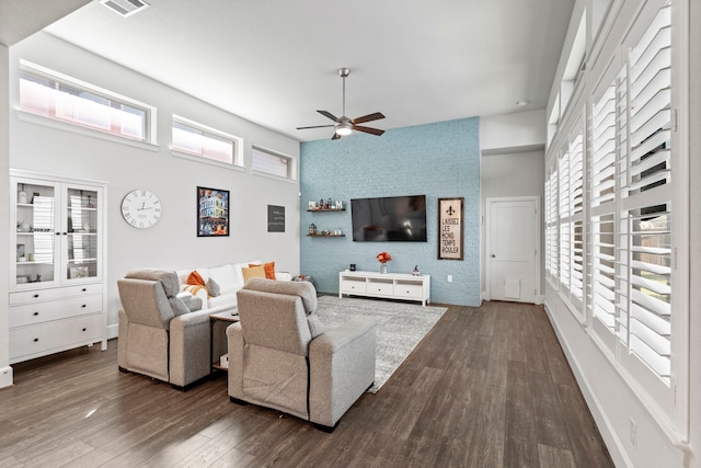 living room featuring dark wood-type flooring, ceiling fan, and a healthy amount of sunlight