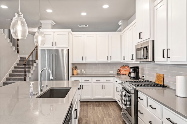 kitchen with hanging light fixtures, white cabinets, stainless steel appliances, and sink