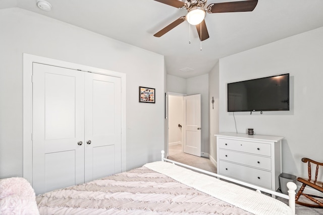 carpeted bedroom with ceiling fan, a closet, and vaulted ceiling