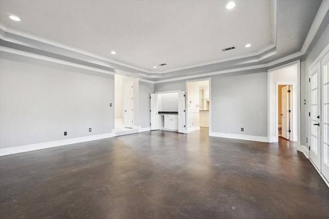 unfurnished living room featuring a tray ceiling, a wealth of natural light, and ornamental molding