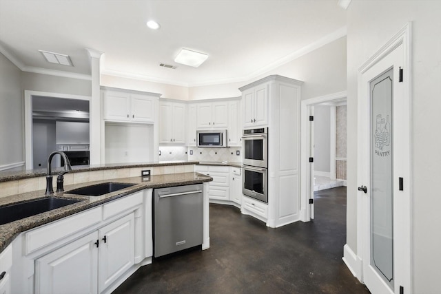 kitchen with white cabinets, dark stone countertops, ornamental molding, and appliances with stainless steel finishes