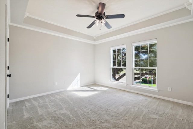 empty room with carpet floors, a raised ceiling, ceiling fan, and ornamental molding